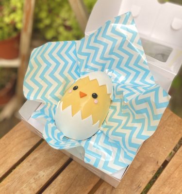 Delicioso Huevo Pollito de Pascua relleno de tentaciones chocolatosas y decorado con un tierno pollito amarillo emergiendo de su cascarón.