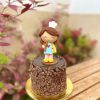 Encantadora mini torta de chocolate decorada con una figura de mamá cocinera y un topper dorado para celebrar el Día de la Madre.
