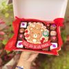 Variedad de postres en una caja decorada con temática de mamá osa para el Día de las Madres.