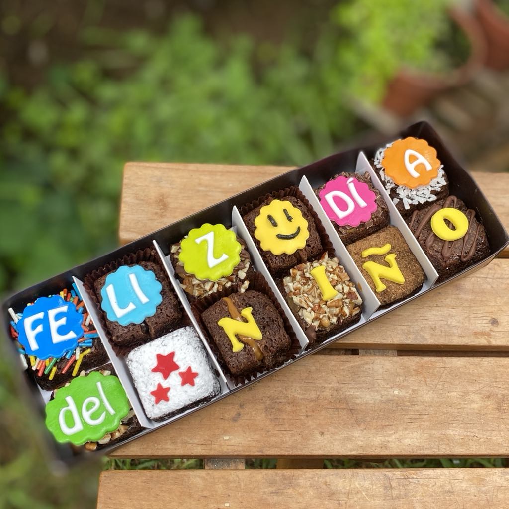 It_bZEr- Doce brownies decorados con fondant y toppings variados, empaquetados en una caja marrón vintage con lazo de tela.