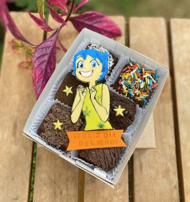 Mini Six Alegría decorado con fondant y toppings variados, empaquetado en una caja ecológica con opción de sticker personalizado.