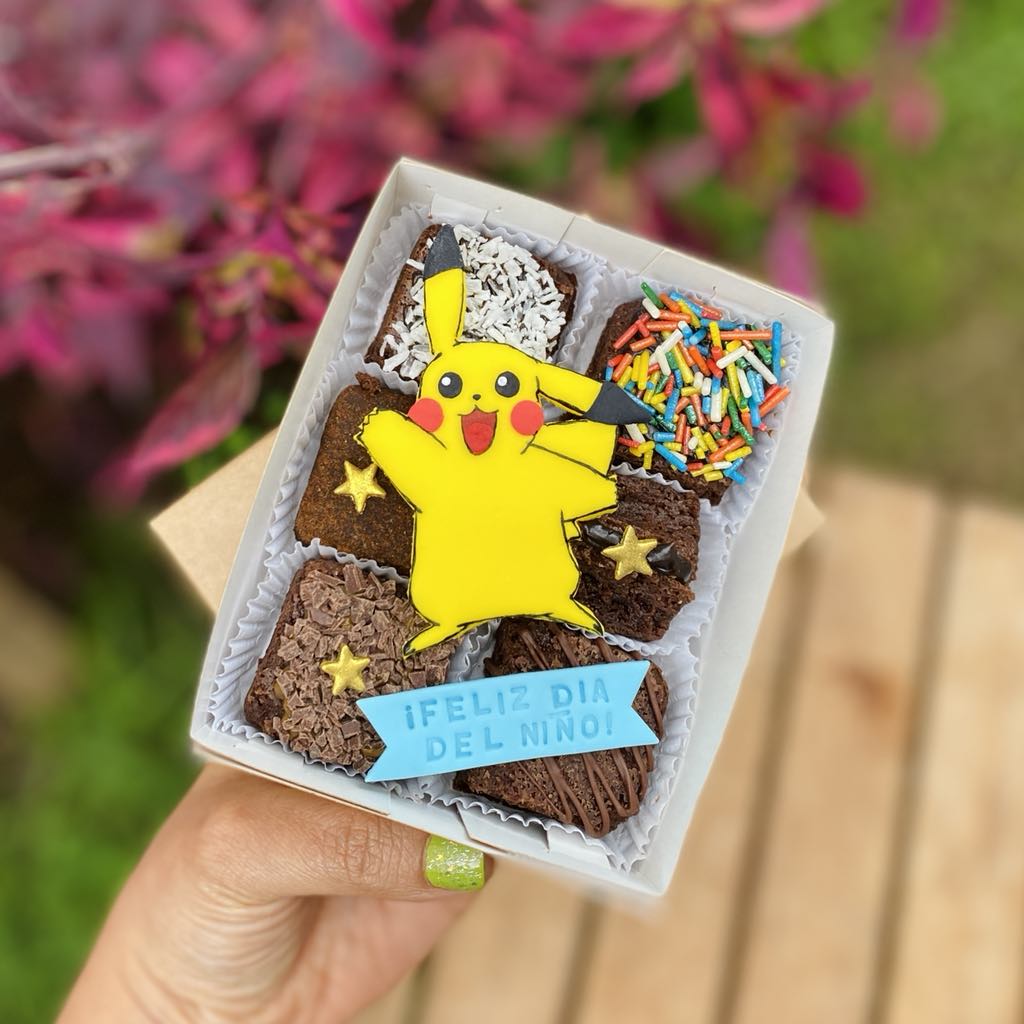 mOj8SqBY Mini Six Pikachu decorado con fondant y toppings variados, empaquetado en una caja ecológica con opción de sticker personalizado.