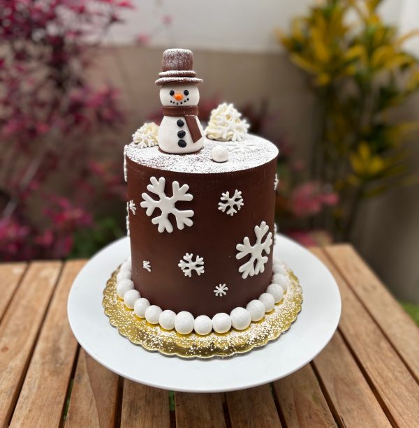 Torta navideña decorada en fondant con diseño de hombre de nieve y detalles invernales.
